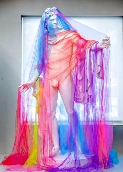 Photograph of a replica of the Apollo Belvedere statue covered in rainbow-coloured tull.