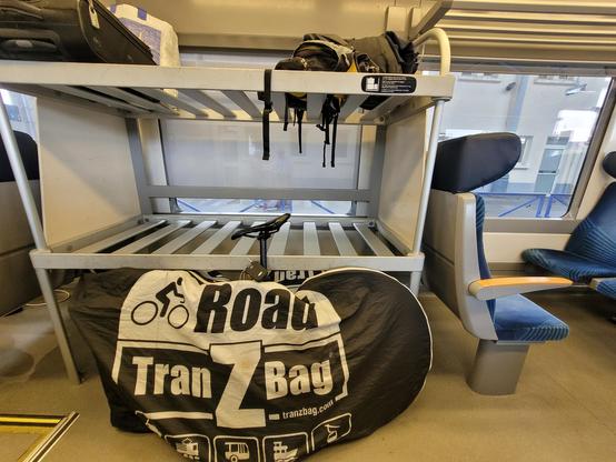 Packed bicycle along a large luggage rack in a Regiolis TER.