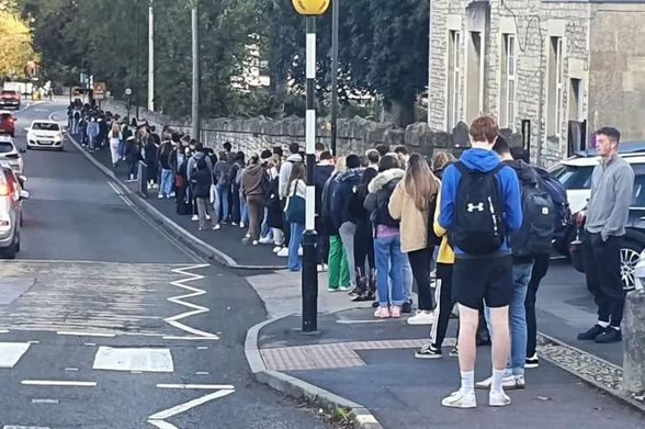 A queue of people waiting on a street for a bus