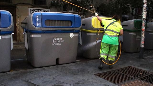 Un trabajador de recogida de limpieza de basura frente a varios contenedores