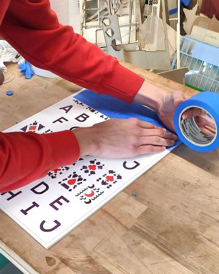 Planches de jetons de jeu de société, sur une table en bois, en train d'être recouverte de scotch
