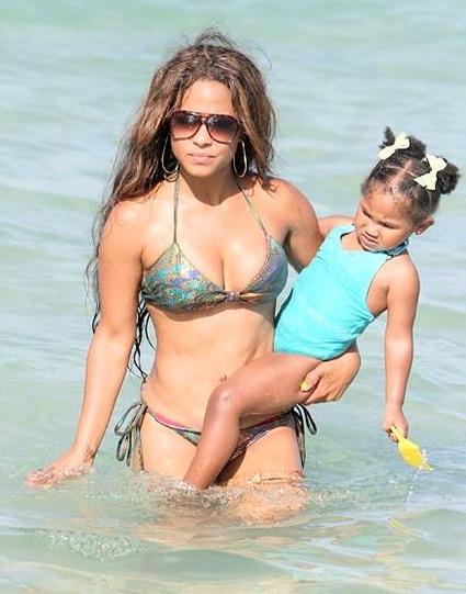Mother and holding her baby girl while standing in the ocean water 