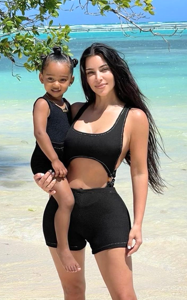 A mother standing in the ocean water holding her baby girl 