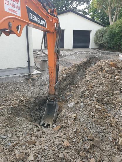 A digger excavating a drain on a driveway.