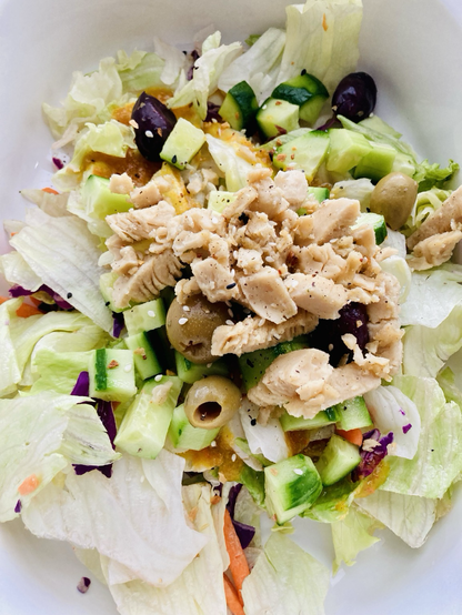 Tasty vegan salad made with iceberg lettuce, cucumbers, olives, Morning Star plant protein strips, ginger vinaigrette, pepper, and seeds 