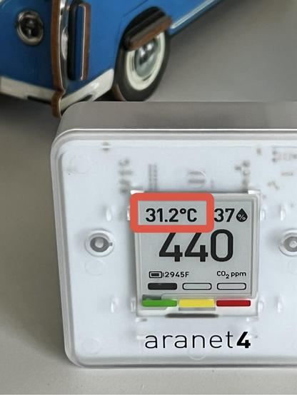 Ein Aranet CO2 Sensor auf einem Schreibtisch. Auf der Anzeige diese Werte: 440ppm CO2, 37% Luftfeuchtigkeit, 31,2°C