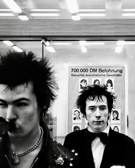 Sid Vicious and Johnny Rotten circa 1978 ... standing in front of Wanted Poster for the RAF 