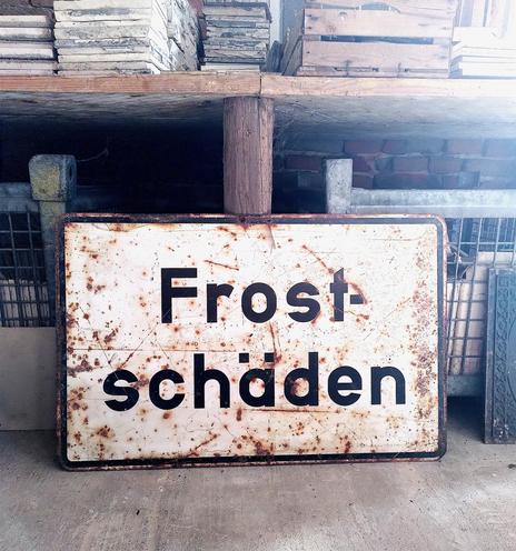 Ein altes, rostiges Schild mit der Aufschrift: Frostschäden.