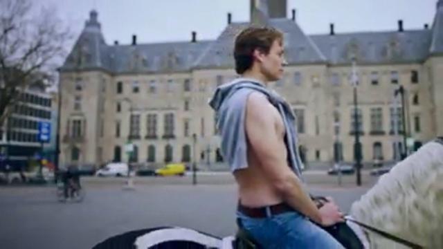 Vincent Karremans met ontbloot bovenlijf, een trui met de mouwen om zijn hals geslagen, rijdt op een wit paard naar het stadhuis van Rotterdam, een mislukte poging tot humor t.g.v. de VVD-verkiezingscampagne aldaar