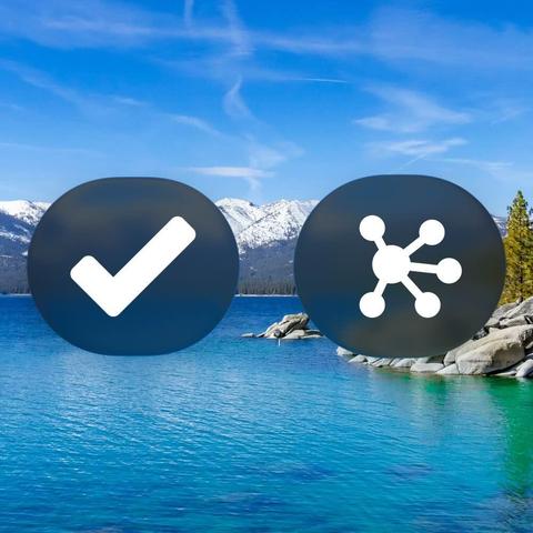 Liquid Glass buttons featuring glyphs representing OmniFocus and OmniGraffle, floating over a background image of Lake Tahoe—alluding to Omni's roadmap and macOS 26 Tahoe. (The buttons are rendered in Dark Mode on beta 2.)