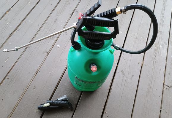 The spray tank is green, and it has a new metal wand section. The broken piece sits on the deck beside it.