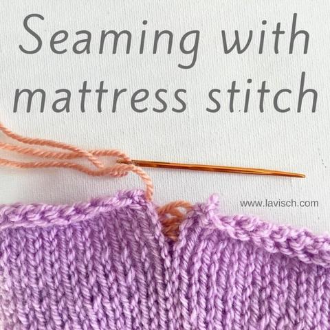 A swatch in lilac yarn being closed with a mattress stitch join using salmon pink yarn.