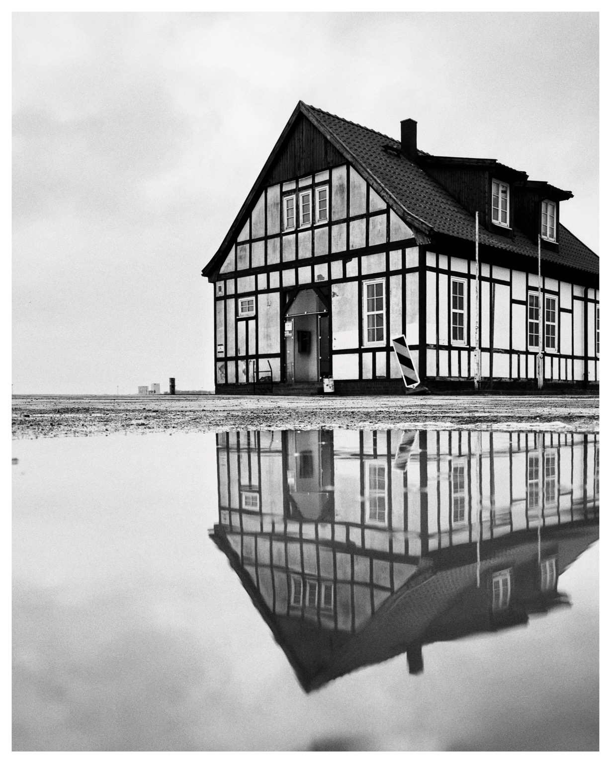 black and white photo of a half-timbered house reflected in a large puddle