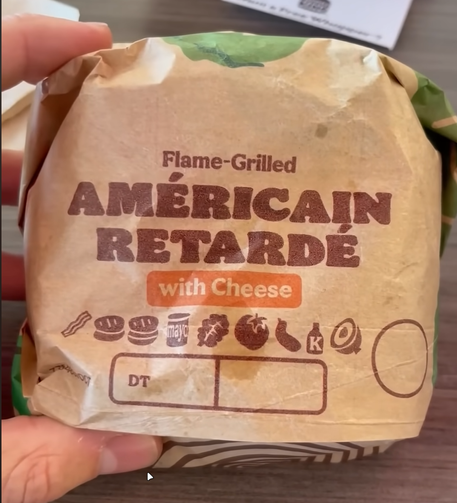 A picture of a french Whopper with the text 
"Flame-Grilld AMÉRICAIN RETARDÉ with Cheese"