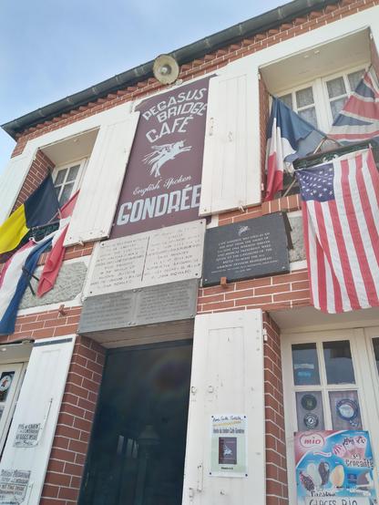 Le Pegasus Bridge Café, couvert de drapeaux belges, français, US, UK...