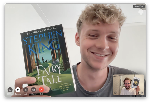 Screenshot of the FaceTime call of Frank and me, both smiling into the camera. Frank is seen pretty big, while my window is small in the bottom right corner. Frank holds a book in his hand, named "Stephen King, Fairy Tale". I hold a book in my hand named "Hideo Kojima, The Creative Gene".