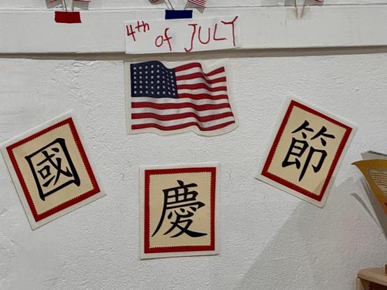Decorations in my kids’ classroom featuring handwritten “4th of July”, the American flag and printouts that say “國慶節”.