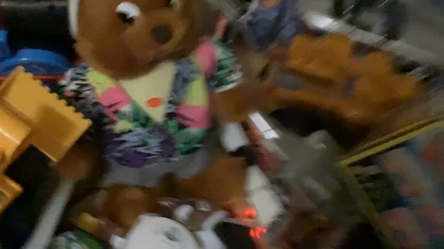 A hand holds a brown cartoonish rabbit, standing up and wearing shorts and a multicolored Hawaiian shirt. The hand presses a button on the chest and it begins moving, shaking its arms alternatingly and wiggling its feet as if to walk, while repeatedly playing a short excerpt of the Macarena. After a while, the hand pushes the button again and it turns off.