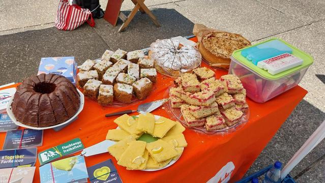 Diverse Kuchen auf einem Tisch mit oranger Tischdecke.