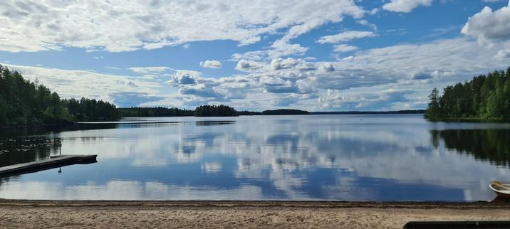 Pihlajaveden Sahanrannan uimaranta. Sinisellä taivaalla pilviä. Hiekkaranta ja laituri.