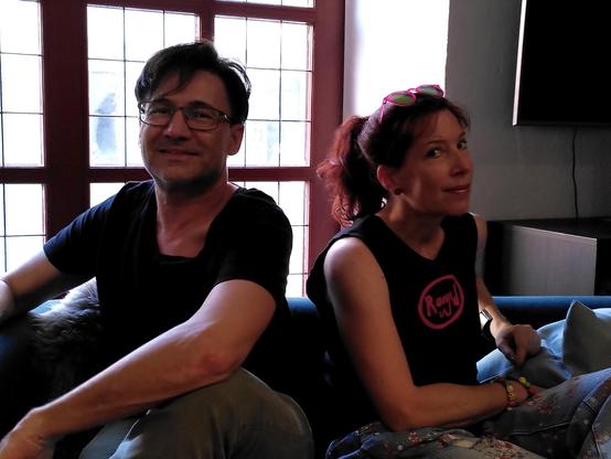 Autor und Autorin sitzen auf dem Sofa und gucken quatschig.