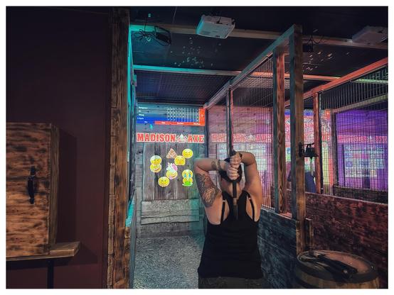 My wife throwing an axe two handed, over head style at a series of emoji targets 