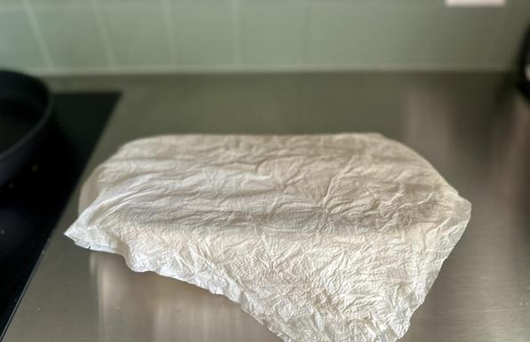 Das Gärkörbchen steht nun mit einem feuchten Küchenpapier abgedeckt auf der Anrichte. Den länglich gewirkten/geformten Teig, der darunter liegt, muss man mehr vermuten, als dass er sichtbar ist.