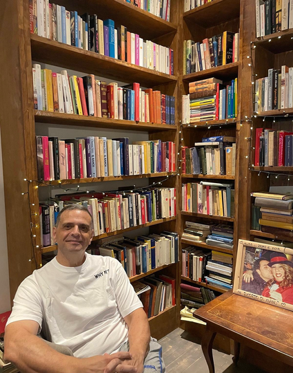 La foto mi vede seduto con alle spalle varie librerie colme di tomi 