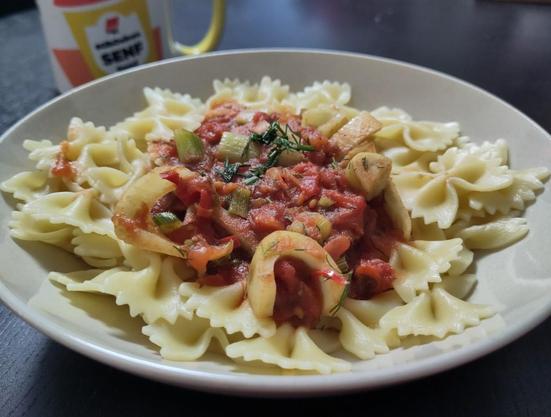 farfalle mit Soße auf dem Teller. km Hintergrund eine Kaffeetasse