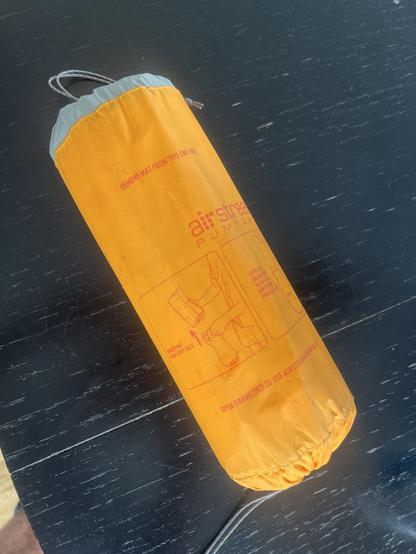 An orange roll with some instructions on red printed on it. One end is grey with some cord attached. 