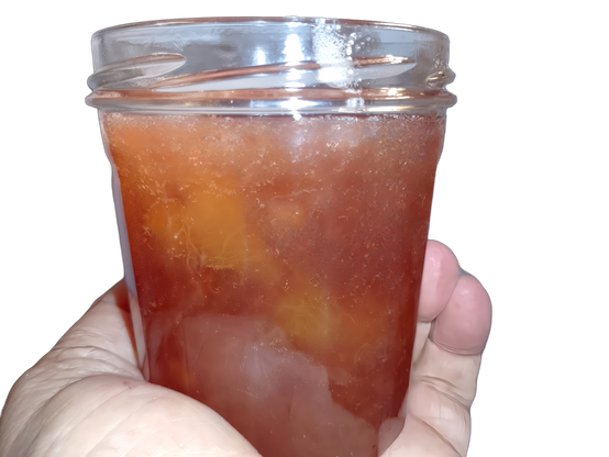 Un pot de confiture de pêches ouvert que je tiens en main.