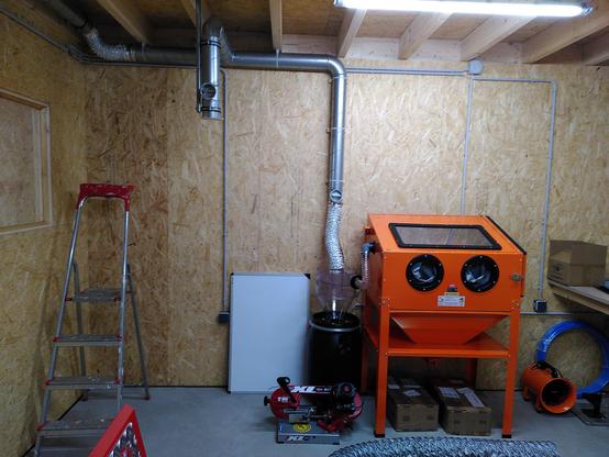 Shoo showing an orange bead blasting cabinet and a dust collection system. Under the roof you can see new ducting for the fume exhaust system.