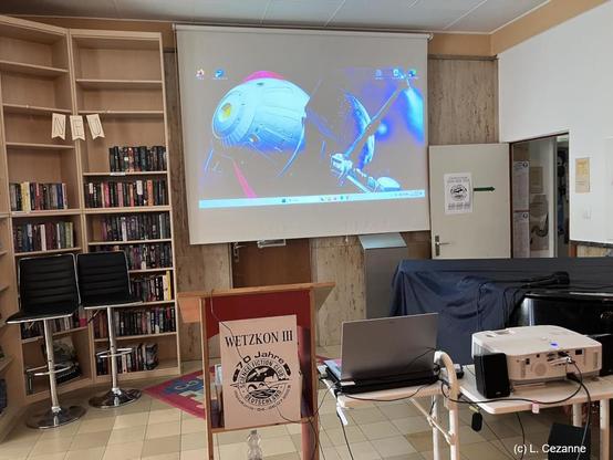Das Foto zeigt den großen Saal der Phantastischen Bibliothek Wetzlar, in der das Programm sowie die Preisverleihung stattfanden. Auf der Leinwand hinten an der Wand ist die COMET als Beamer-Projektion zu sehen - das Bild entstand kurz vor Beginn unseres Vortrags...
