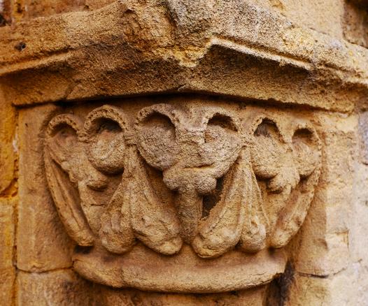 Stone carving in yellowish sandstone, with three heads with antlers, bulging eyes and long noses. In between them are decorative swags, the top part of which bears small holes and the bottom rather pendulous.