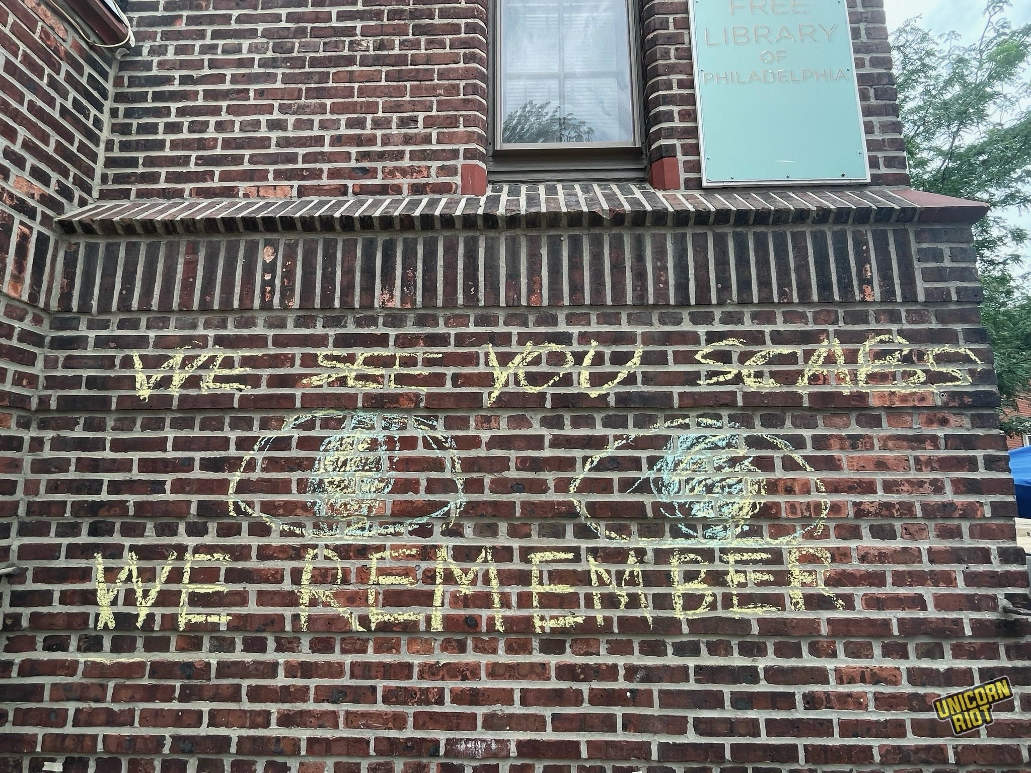 "SCAB LINE" and "WE SEE YOU SCABS - WE REMEMBER" written in chalk on the brick entrance to the library