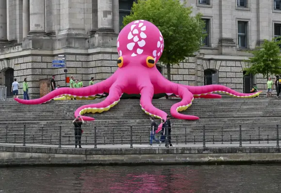 Large inflatable pink octopus with white spots on the steps of a building.