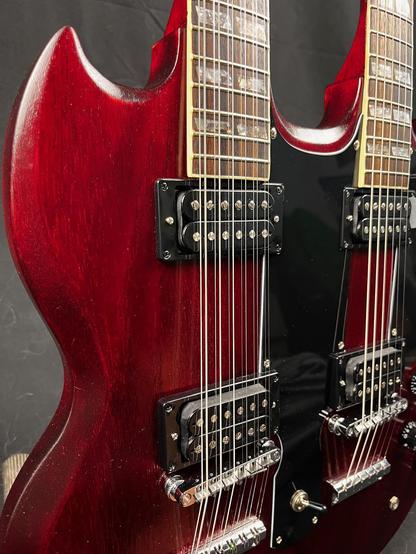 Eine Doppelhalsgitarre, roter Body, Detailaufnahme schräg von der Seite. Die Gitarre hat einen Hals mit 12 Saiten und einen mit 6 Saiten und ist der berühmten „Stairway to heaven“ Gitarre von Jimmy Page nachempfunden.