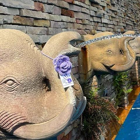 a knittet purple rose on a elephant out of stone in a temple in bangkok, thailand
