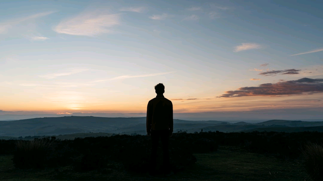 A silhouette of a figure with a sunset in the background