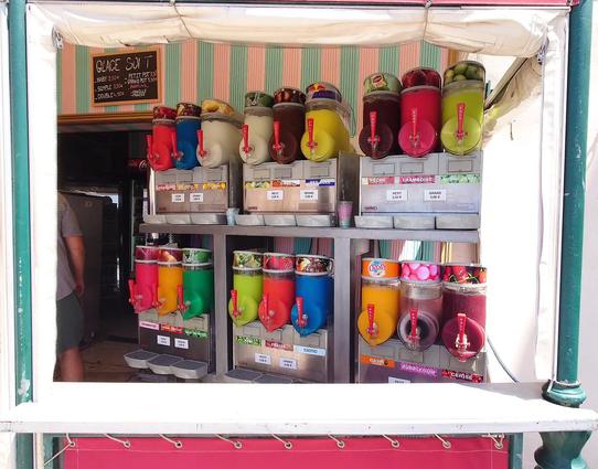 Blick in einen Kiosk mit 18 Zapfgeräten in unterschiedlichen Farben, die jeweils eine Geschmacksrichtung Granita haben. 