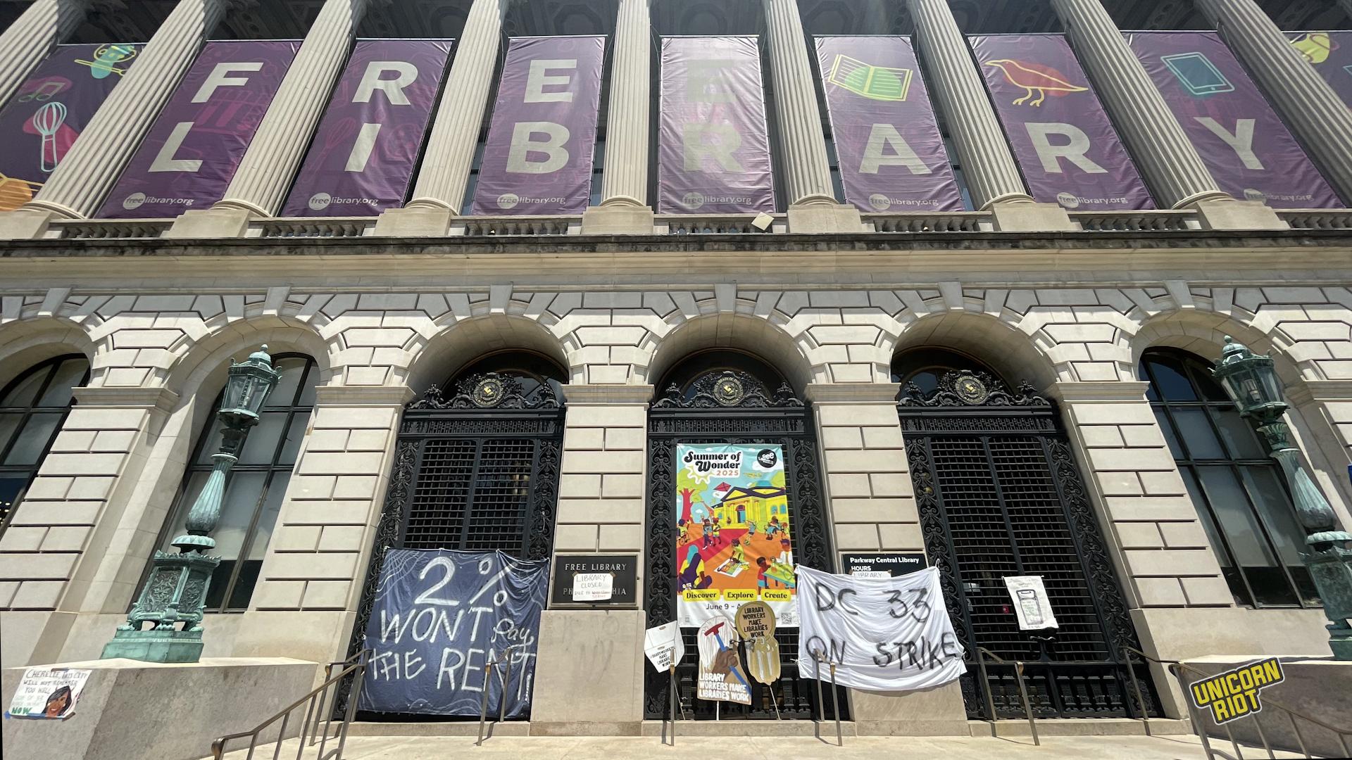 The main entrance of the Parkway branch of the Free Library of Philadelphia seen from below with "2% won't pay the rent" and "DC 33 on strike" banners placed in front of the entrance gates