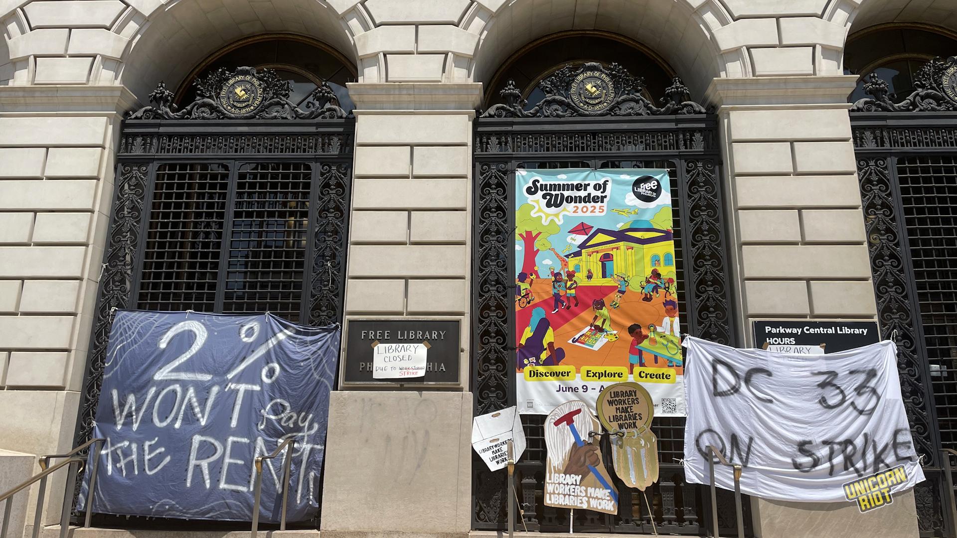 The main entrance of the Parkway branch of the Free Library of Philadelphia seen from below with "2% won't pay the rent" and "DC 33 on strike" banners placed in front of the entrance gates