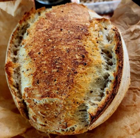 A boule loaf of spurdough with two ears on a board. 