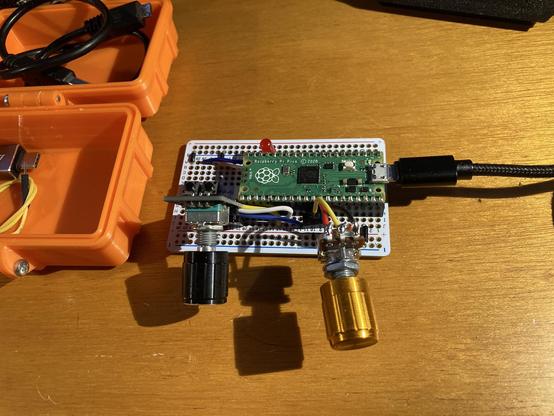 A protoboard with a controller next to a 3D printed rugged box.