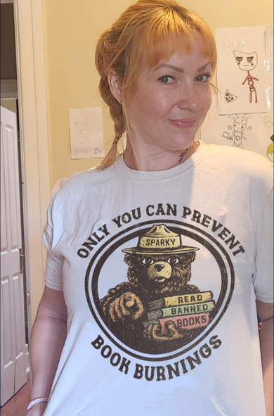 Woman wearing a t-shirt that says Only You can prevent book burnings 
