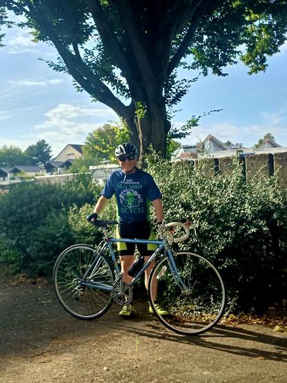 I'm in my riding clothes standing in front of a tree behind my blue 1986 KHS road bike just before dinnertime post-ride today.