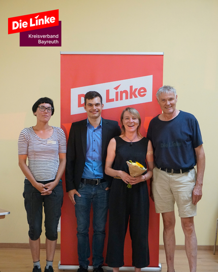 Vier Personen stehen nebeneinander vor einem roten Die-Linke-Rollup. Von rechts nach links: Eckard Sabarth (Platz 1), Christin Siegel (Platz 2), Jannick Metz (Platz 4) und Nicole Richwald (Platz 3) – die ersten vier Listenplätze der Stadtratsliste von Die Linke Bayreuth. Alle blicken lächelnd in die Kamera.

