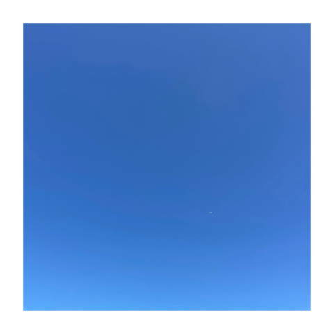a photograph of a cloudless blue sky with a tiny aircraft portrayed as a tiny white dot in a sea of blue
