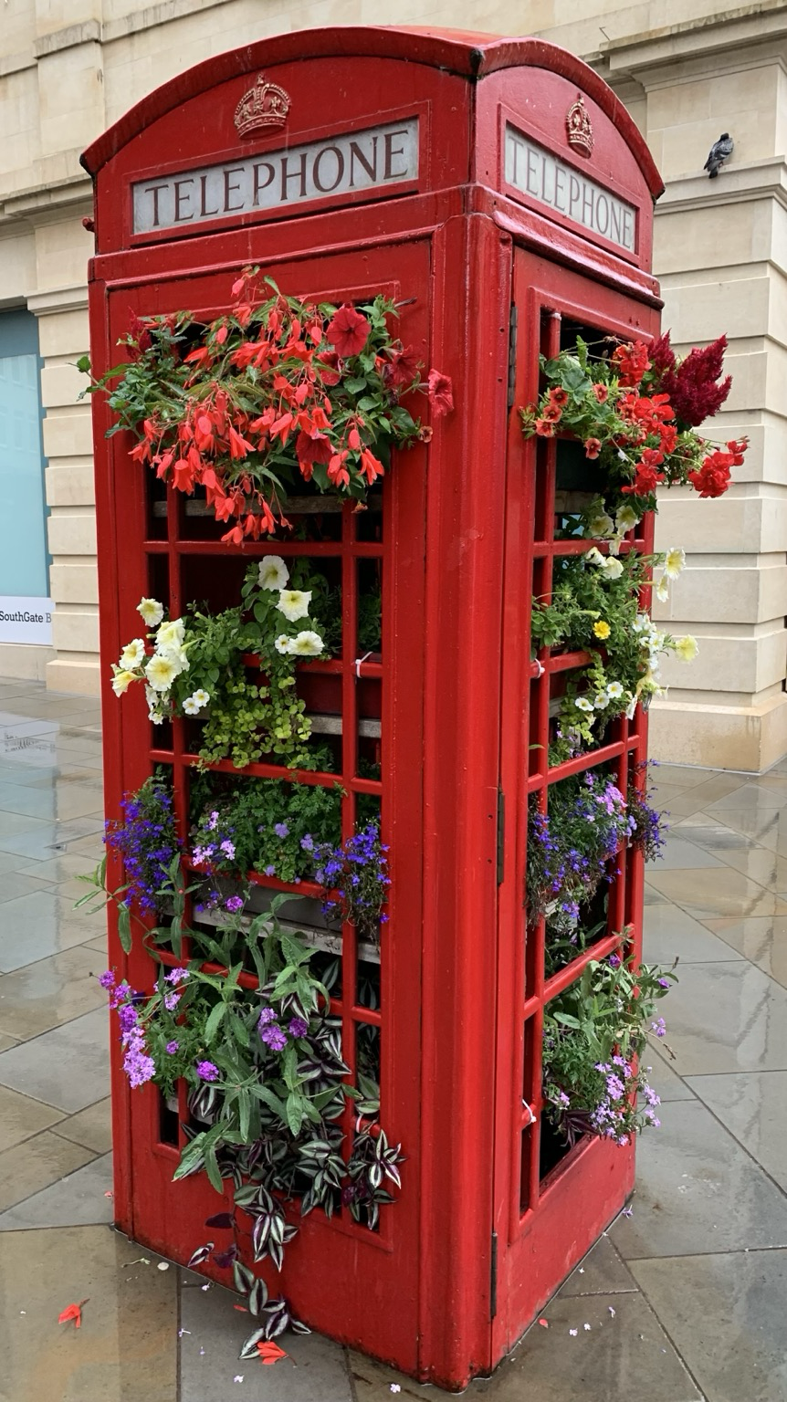 Traditionelle englische Telefonzelle in Rot, komplett bepflanzt mit Blumen.
