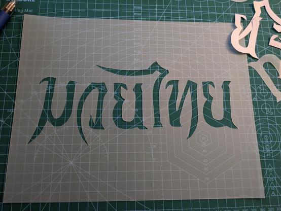 The letters completely cut out and paper removed revealing plastic sheet underneath to be used as a stencil.